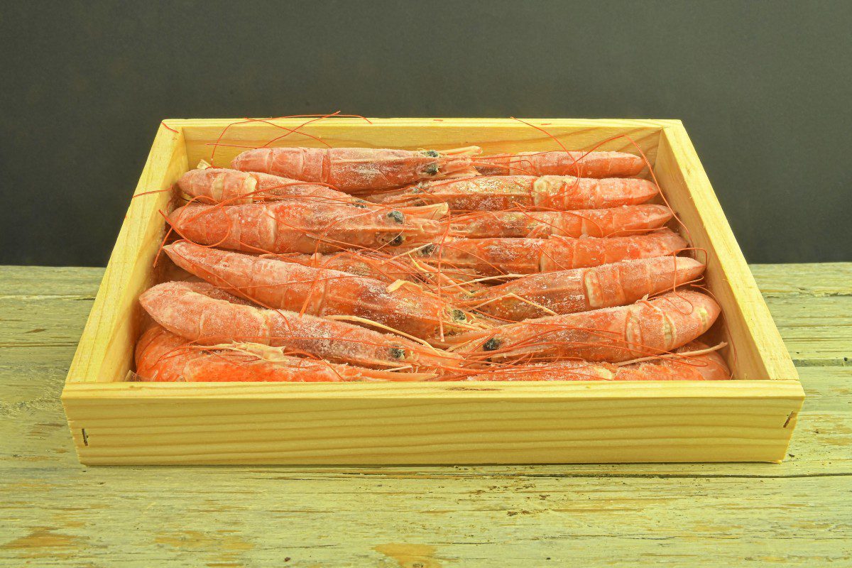 Box of fresh prawns on wooden table.