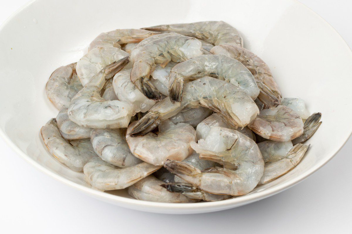 Raw shrimp piled in a white bowl.