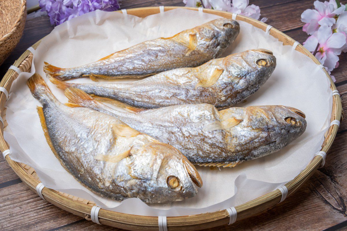 Four dried fish on a round basket.
