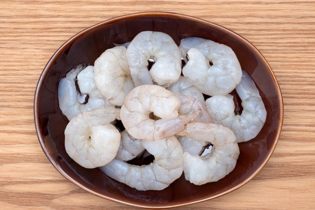 Raw shrimp on a brown oval plate.