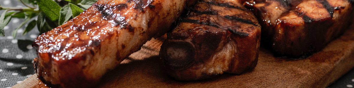 Grilled steaks on a wooden serving board.