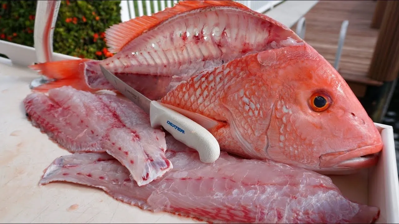 Filleted red fish with knife on board.