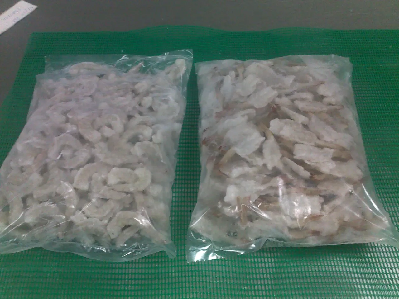 Frozen shrimp in plastic packaging on mat.